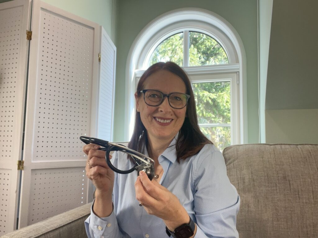 Séverine Mazur, professionnelle de santé souriante tenant un stéthoscope dans un environnement lumineux, prête pour une consultation.